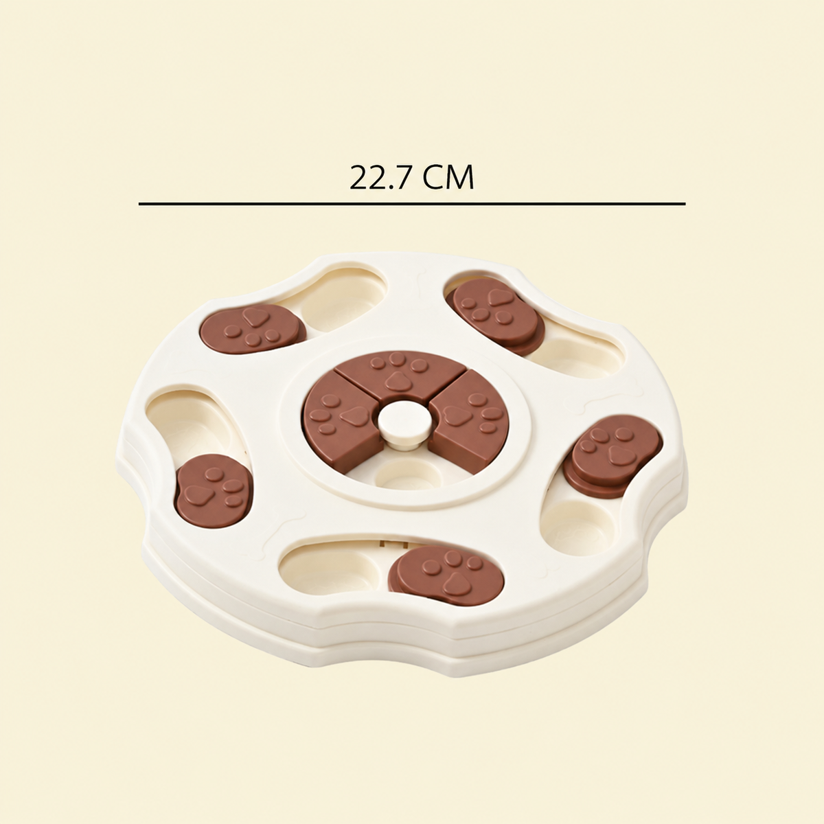 A pet puzzle toy with a white base and brown paw-print shaped pieces, shown on a light beige background with a dimension label reading 22.7 CM.
