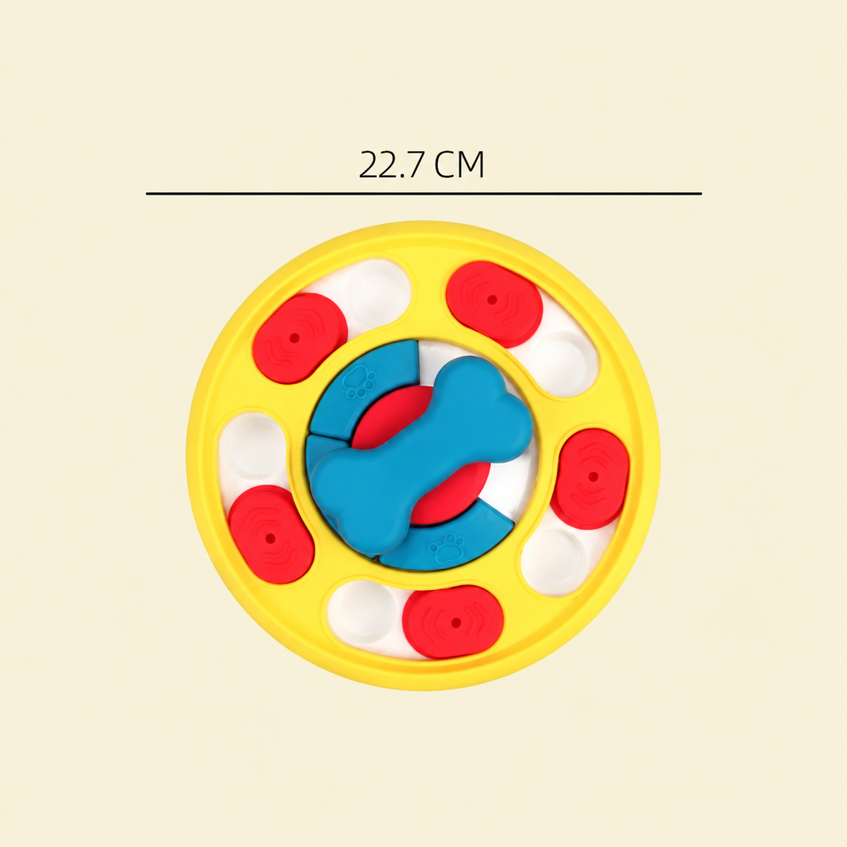 A colorful circular dog toy with a yellow outer ring, red and white oval pieces, and a blue bone-shaped piece in the center. A black horizontal line above the toy shows the measurement '22.