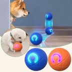 LED light-up dog toy balls shown with two dogs, including a Shiba Inu and a white puppy, on a wooden floor. The image features three balls: two blue balls with glowing blue light patterns and one orange ball with glowing pink light patterns.